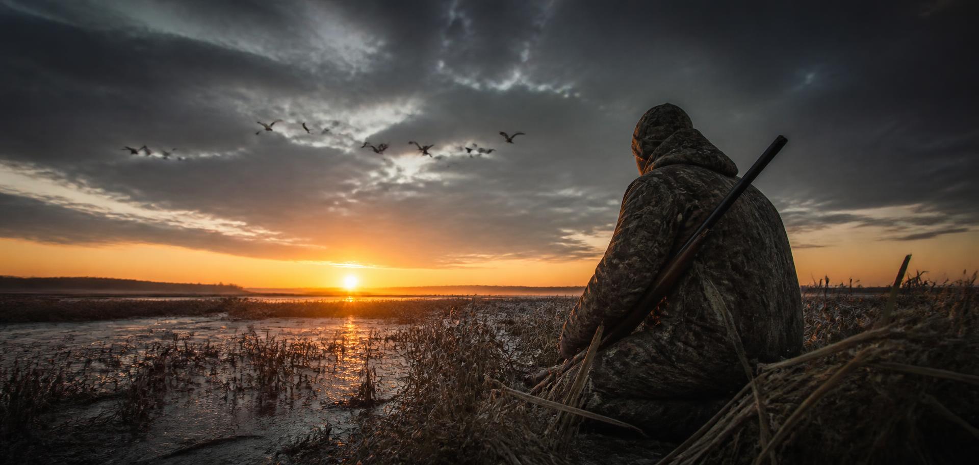 Hunter in a frozen marsh at sunrise